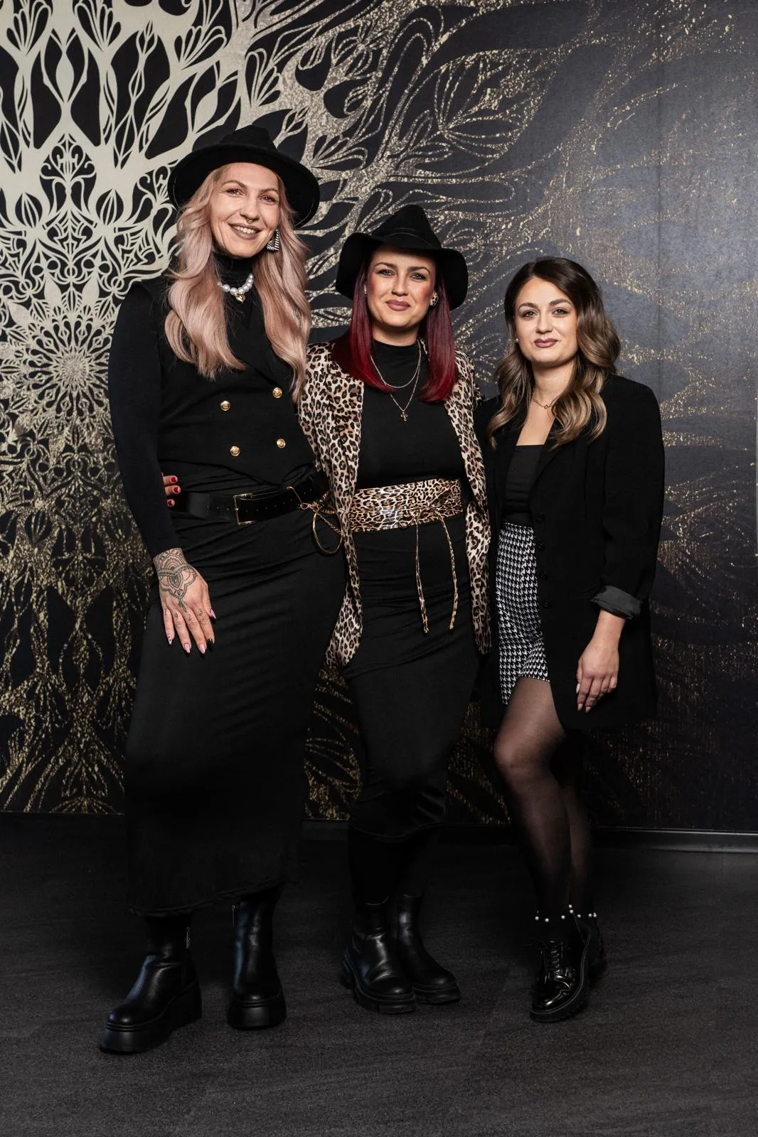 Das Team in editorialer Pose vor dem floralen Salon-Wandbild